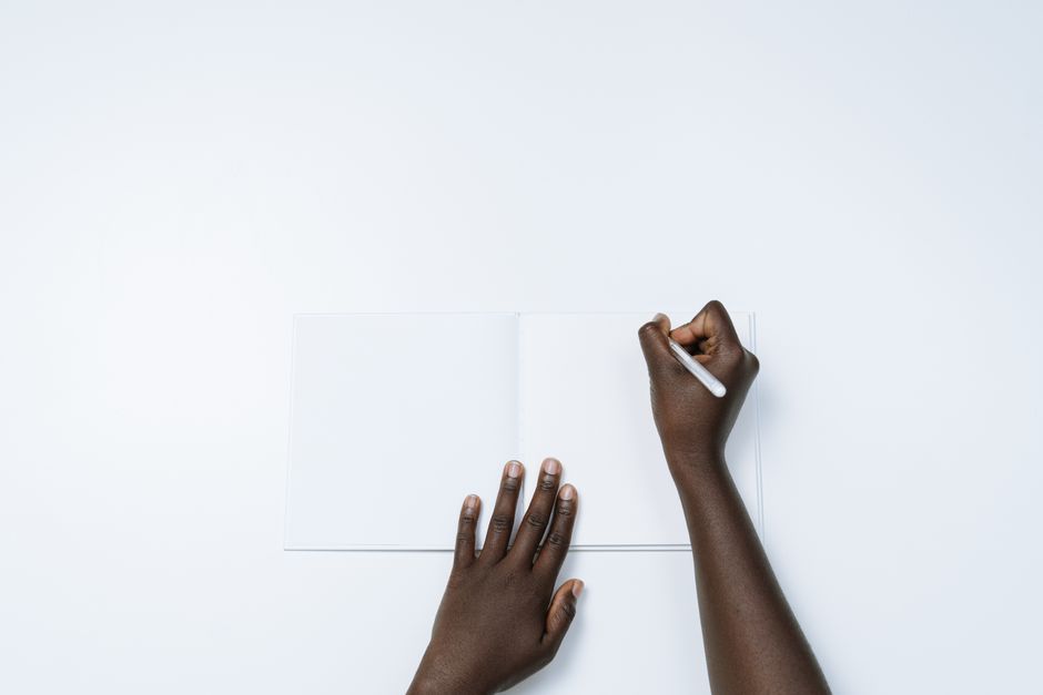Close-up of a host's hand writing a personalized welcome note for a guest on high-quality paper.